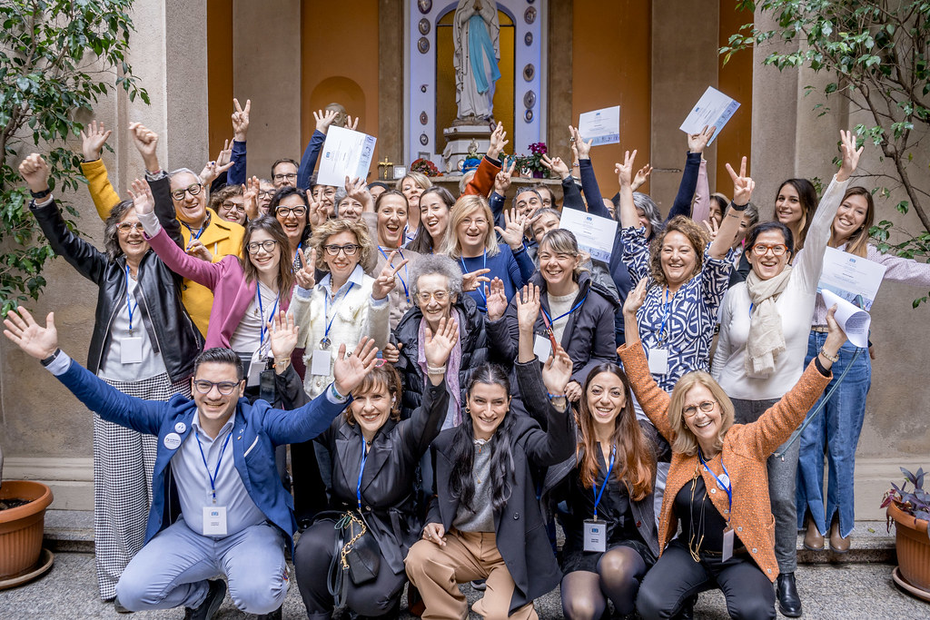 Un gruppo di persone sorride e saluta davanti alla fotocamera
